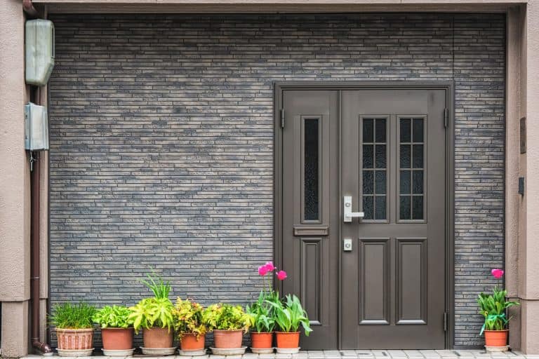 A gorgeous gray themed front porch decorated with flowers in front, Do Doors Come With Holes For Handles?