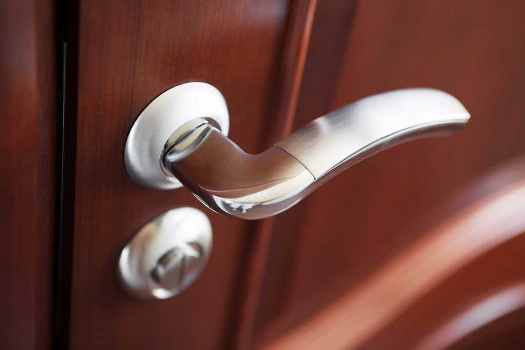 The metal door handle on a brown door
