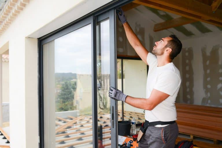 handsome young man installing fiberglass door in a new house construction site, How To Fix A Dent In A Fiberglass Door
