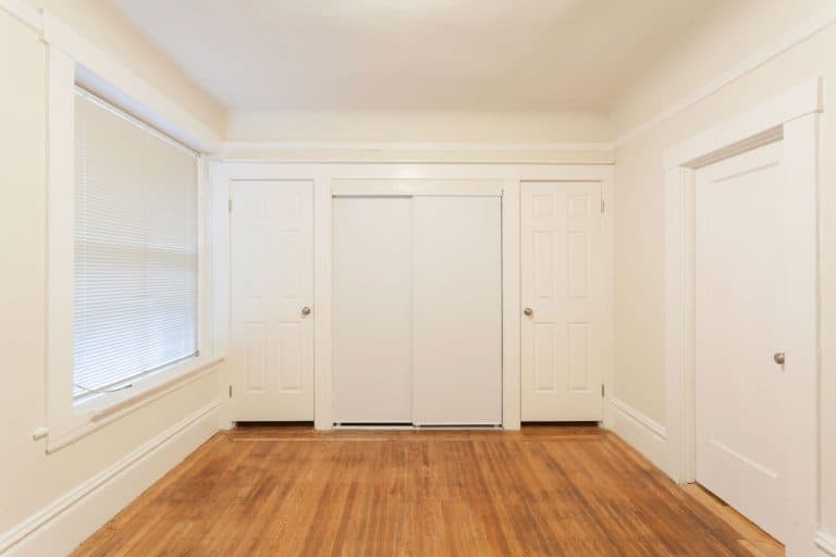 Interior of a white painted room with wooden flooring and a pocket door on the middle, Can You Lock A Pocket Door?