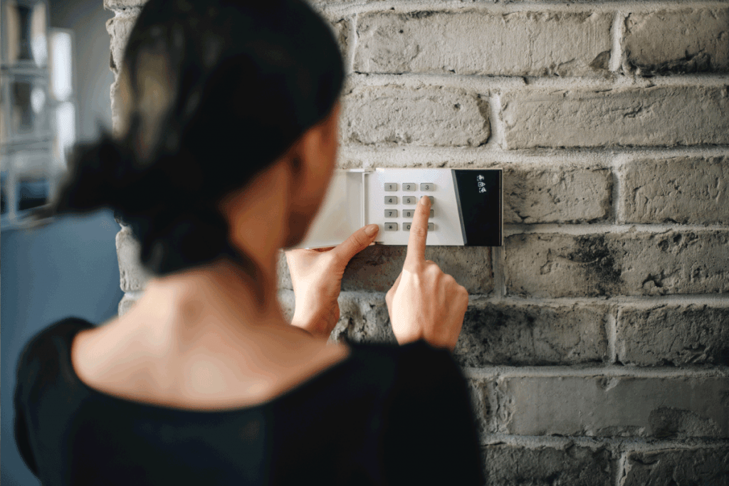 Young woman entering security pin on home alarm keypad. Home security system. How To Stop Alarm From Beeping When Door Opens