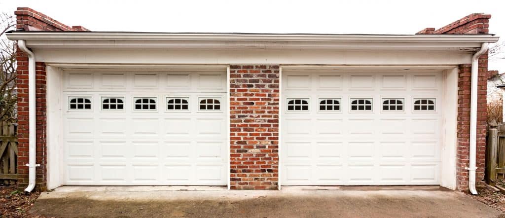A two way garage door painted in white and decorative brick stone in the walls