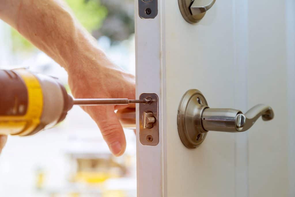 A worker installing a deadbolt lock on the front door
