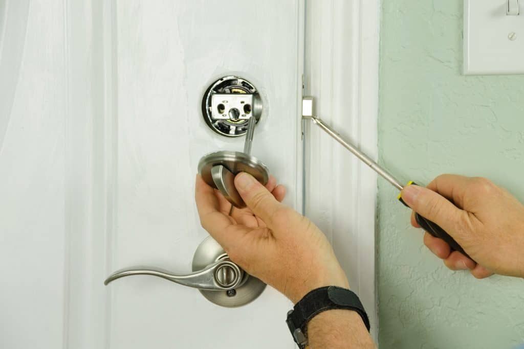 A worker installing a deadbolt lock on the bedroom door