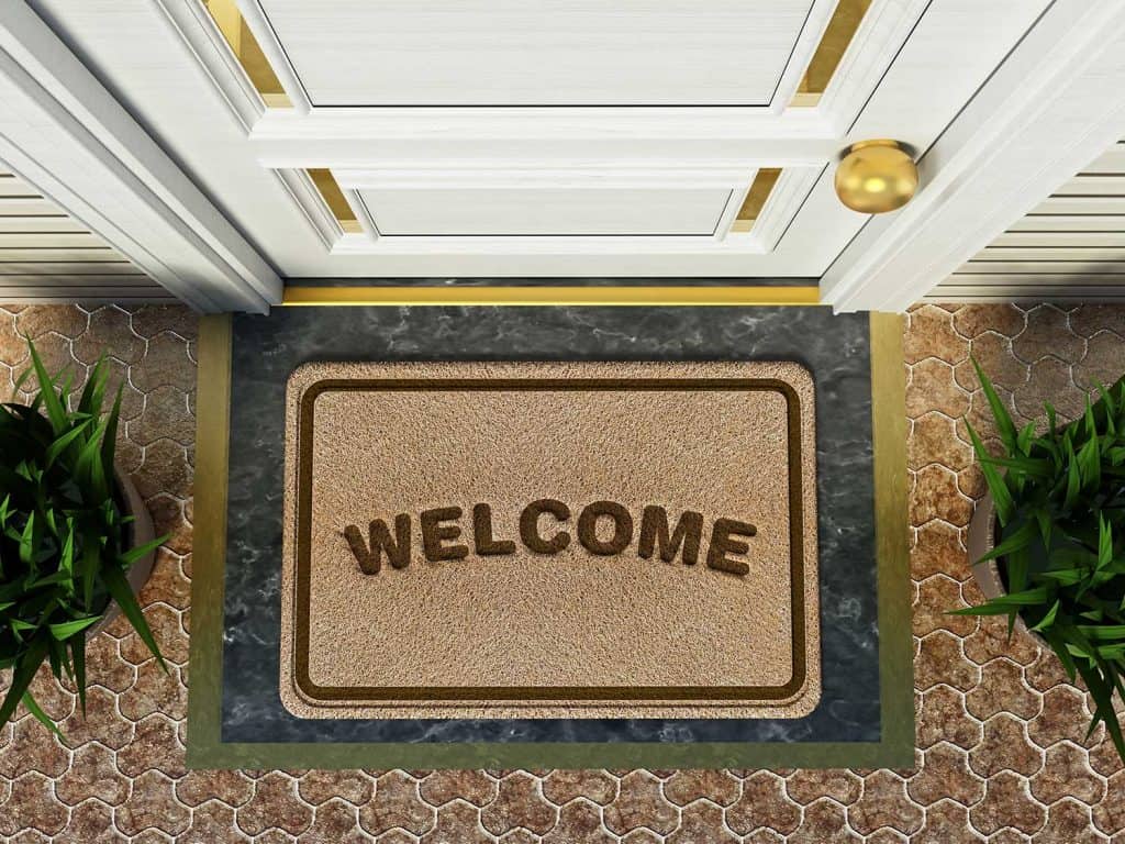 Door mat with welcome word standing in front of the house door