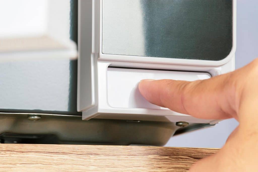 Finger is pressing a button to open the door of the microwave oven