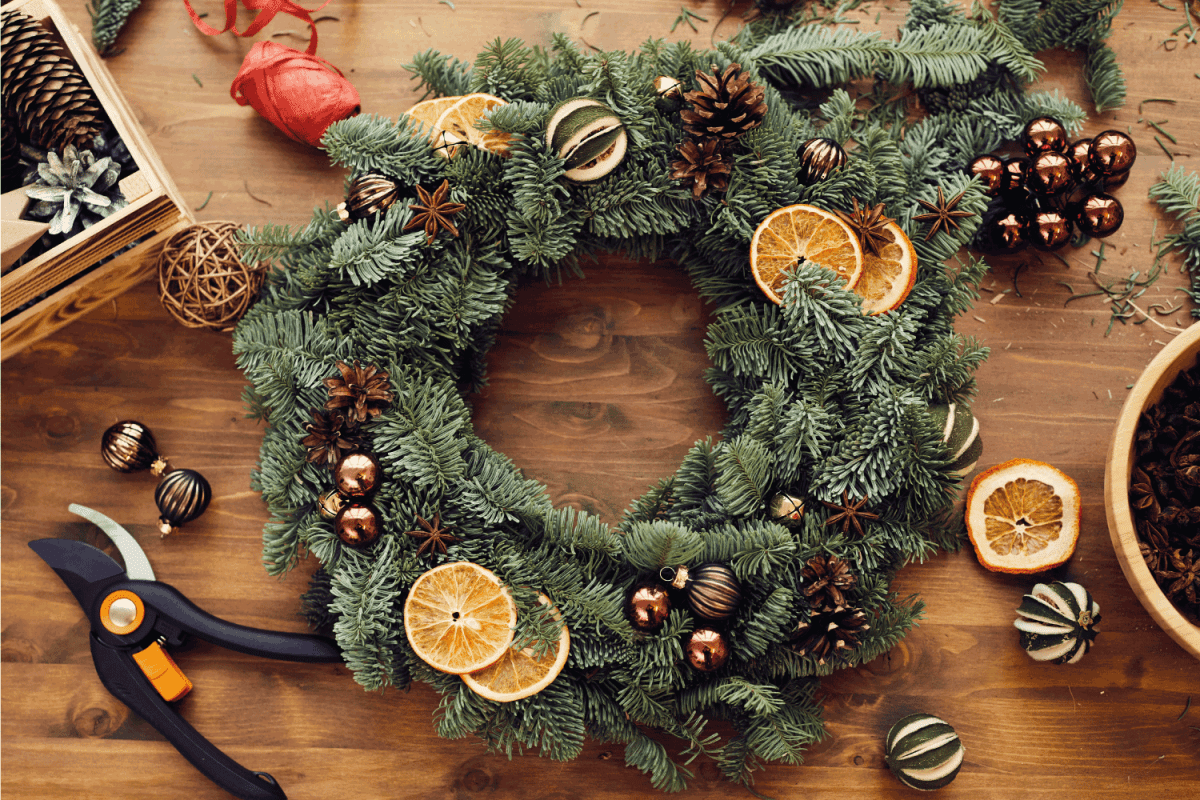 High angle view of beautiful holiday wreath decorated orange slices, fir tree cones and small balls placed on wooden table