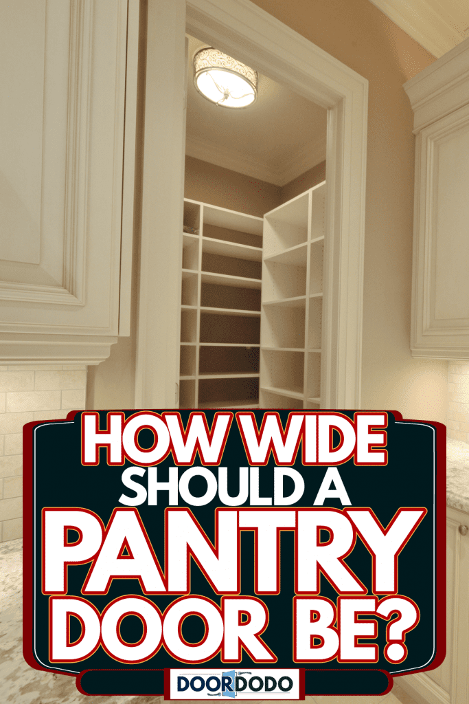 A gorgeous kitchen with an empty pantry and a marble countertop and cream cabinetry, How Wide Should A Pantry Door Be?