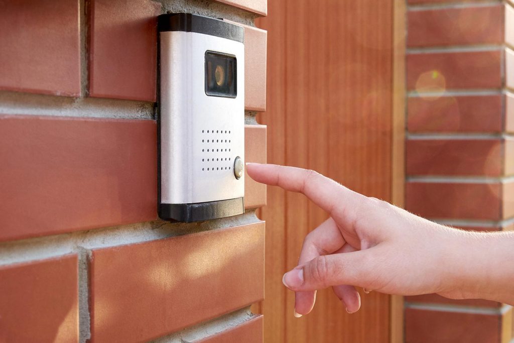 Female hand presses a button doorbell with camera and intercom