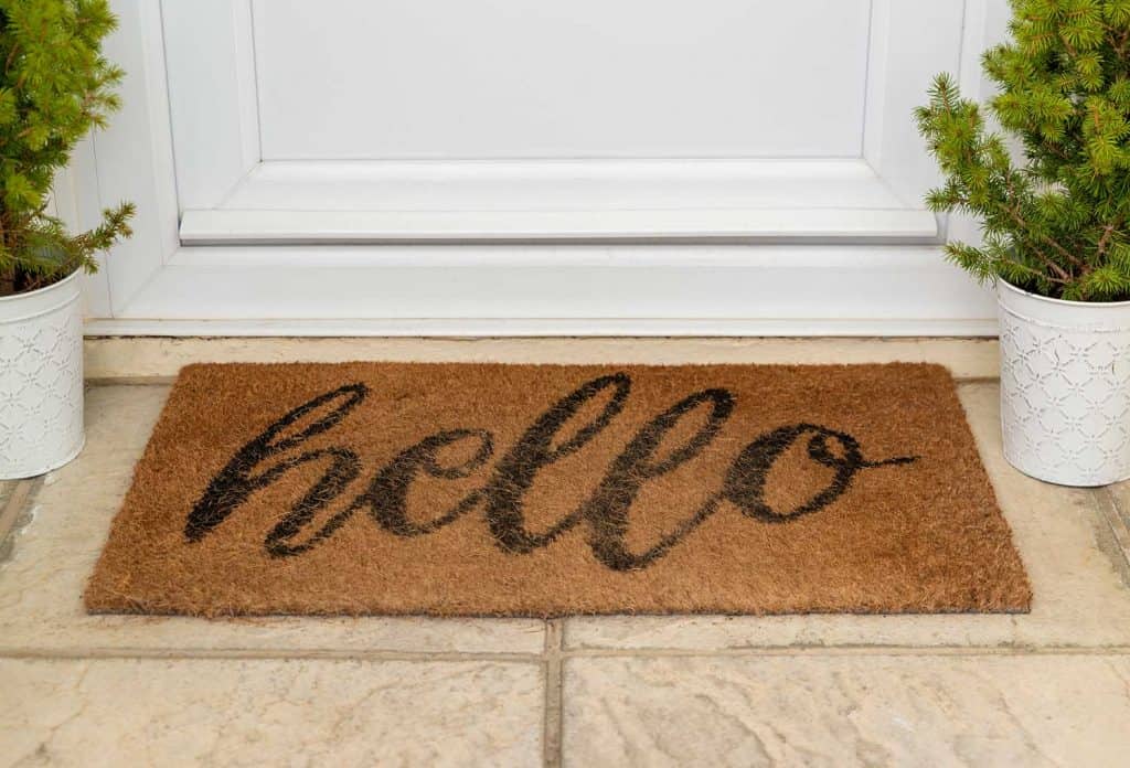 Welcome mat says Hello by a front door