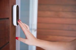 Woman ringing front doorbell equipped with security video camera, 3 Types Of Doorbells