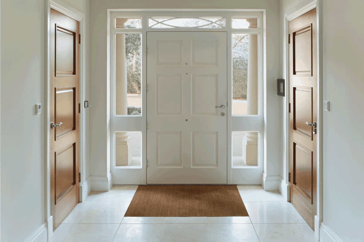 a front door entrance to a grand house. The wood panelled front door and frame are painted white