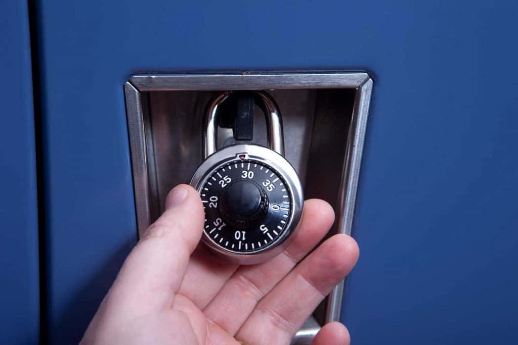 A hand holds a combination lock on a school locker