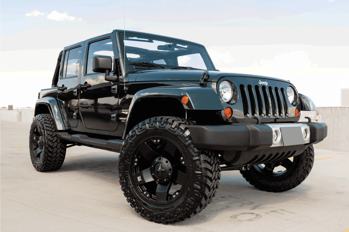 A parked green Jeep Wrangler, this particular Jeep has a custom lift kit and wheels.