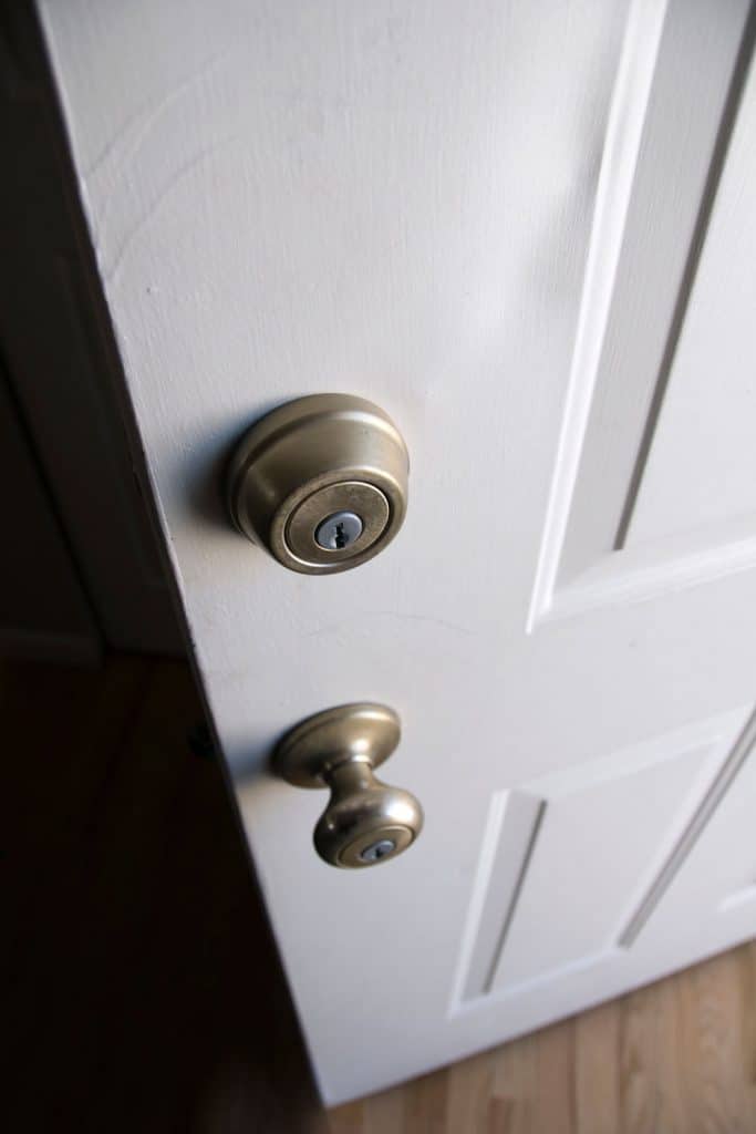 A white front door and a doorknob with deadbolt lock