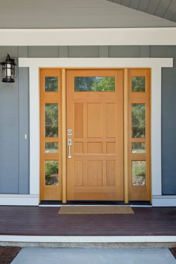 A wooden storm door with glass panels on the sides and white framing