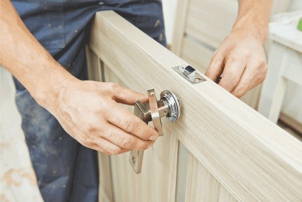 Carpenter at door lock installation. How Long Does It Take To Install A Door