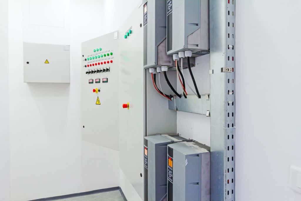 Electrical panel boards in the electrical room with green blinking lights on the panel door