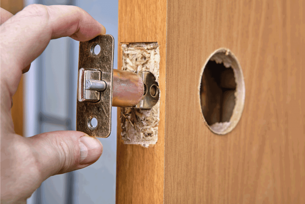 carpenter pulling out deadbolt latch from assembly. How To Cover Deadbolt Hole In A Door