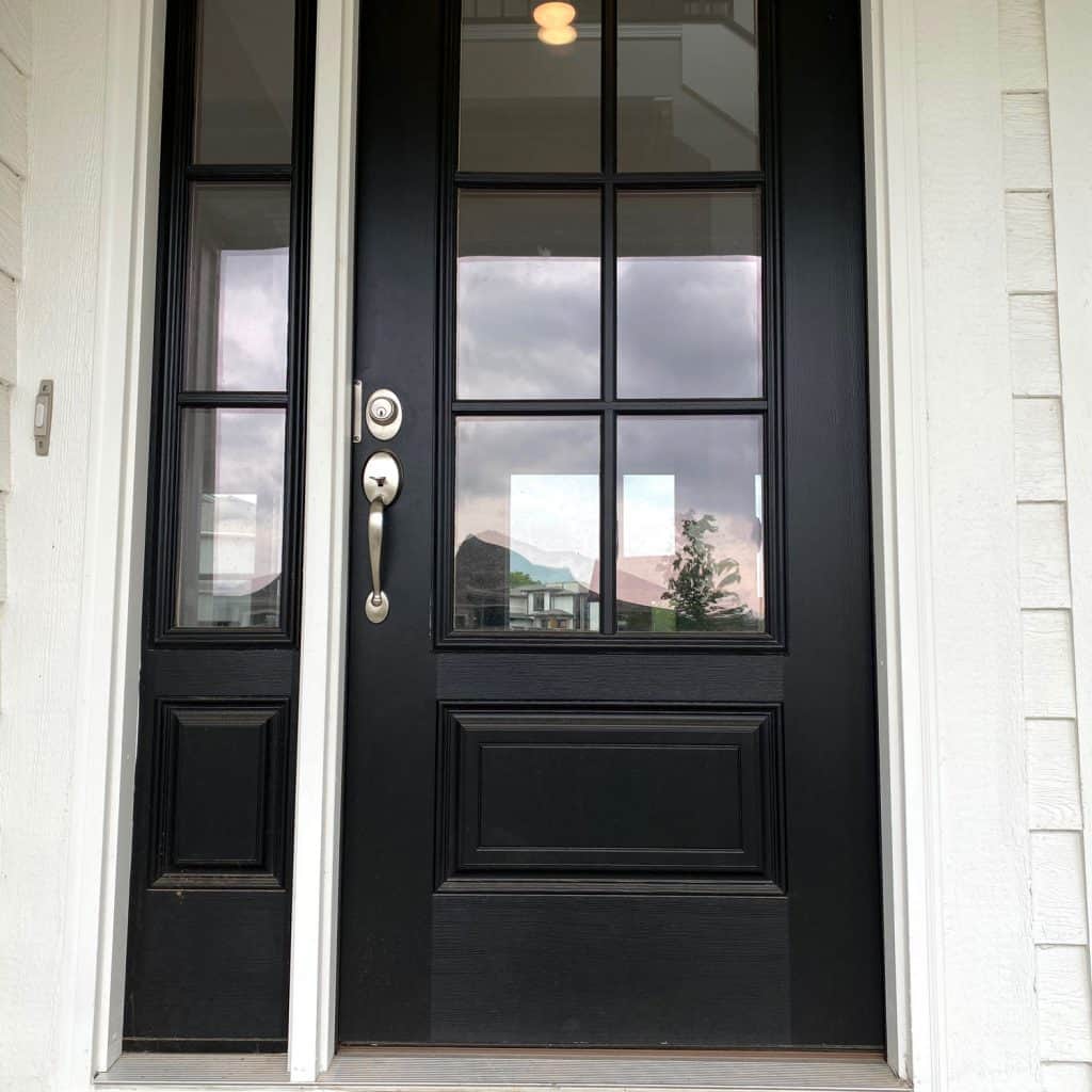 A black front door with a small glass pane on the side