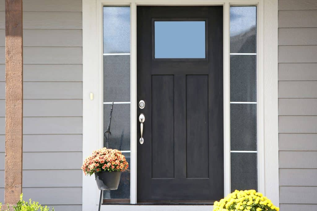 A black front door with silver hardware and glass panes with frost