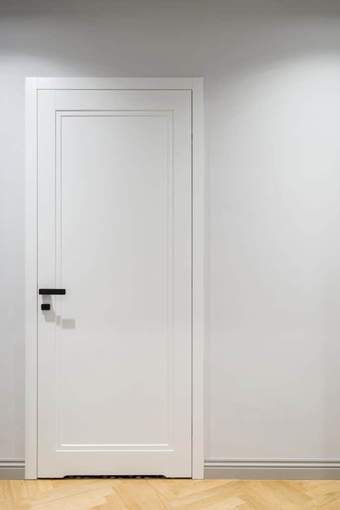 A white door with wooden flooring and gray painted walls