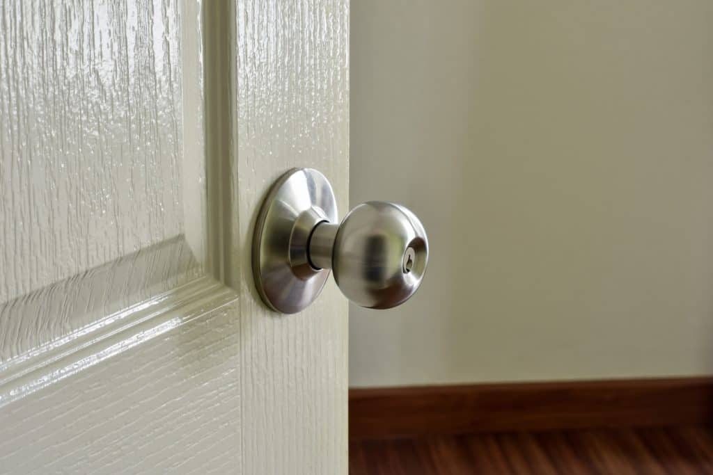 An open white door with silver door knob