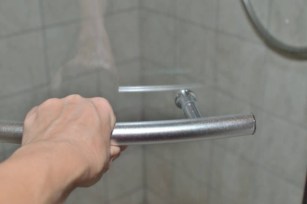 Hand on a door handle of a glass shower cabin in order to open or close it

