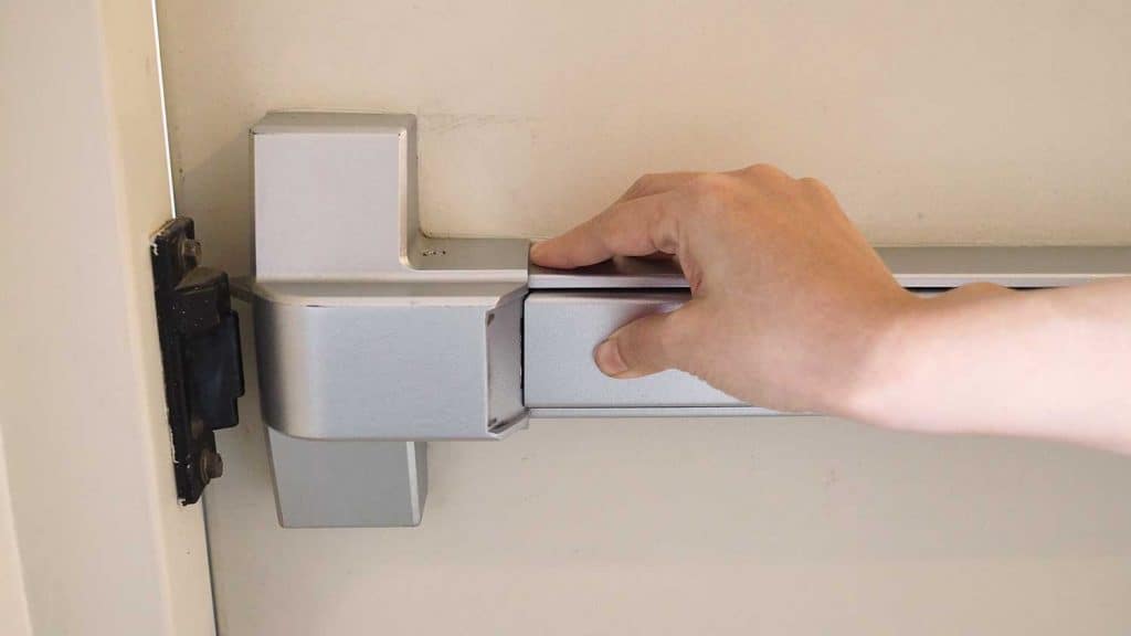 Hand pushing fire door handle of fire exit