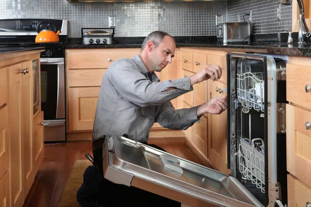 Worker repairing energy efficient dishwasher
