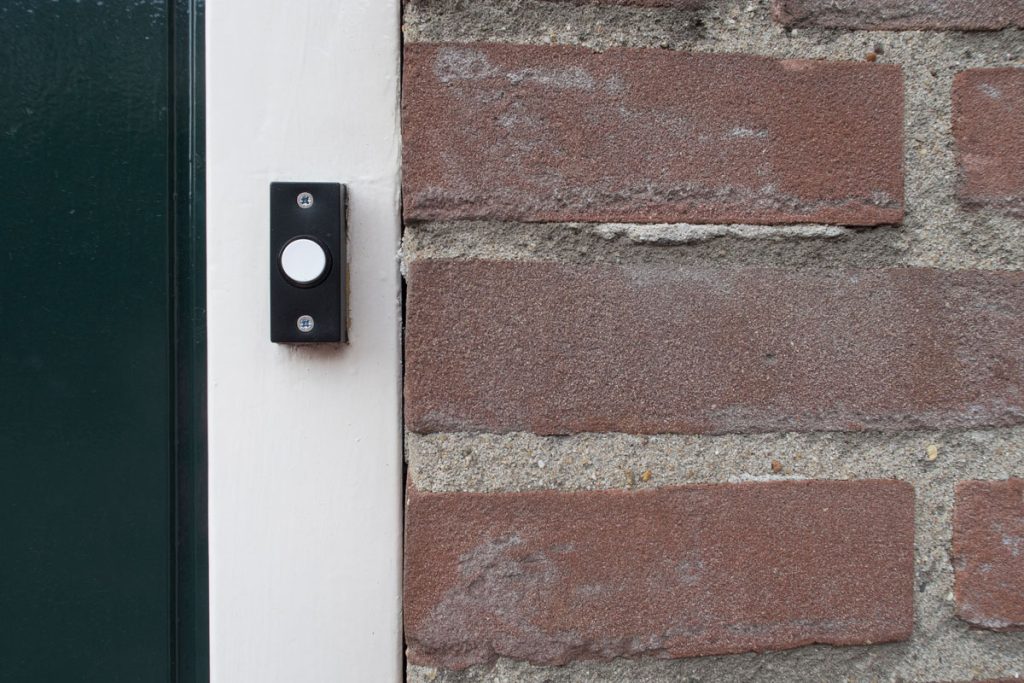 A black door bell mounted on the door frame