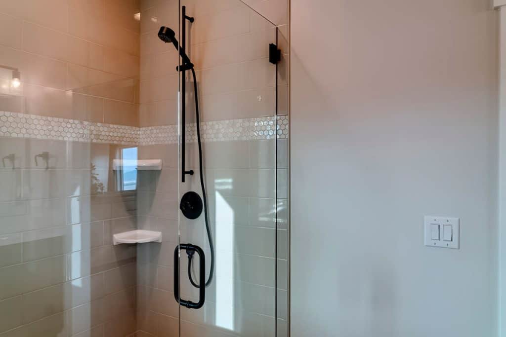 A glass shower door and black door handles and fixtures