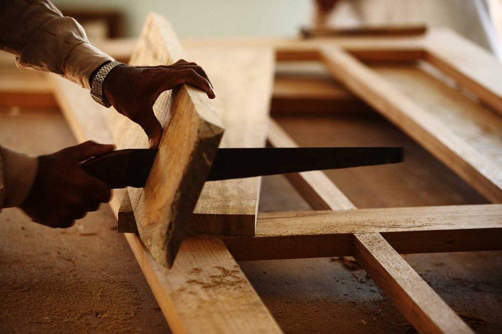 Carpenter is making a panel door frame of teak wood in a room of under construction house