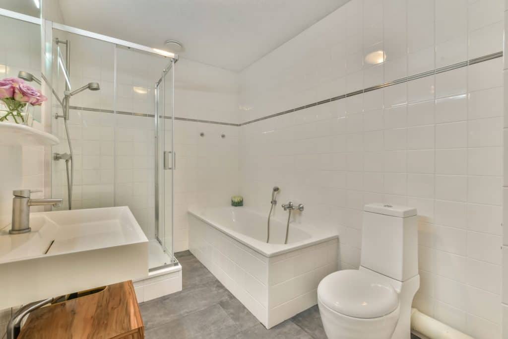 Interior of a modern bathroom with a glass walled shower area and whit painted walls