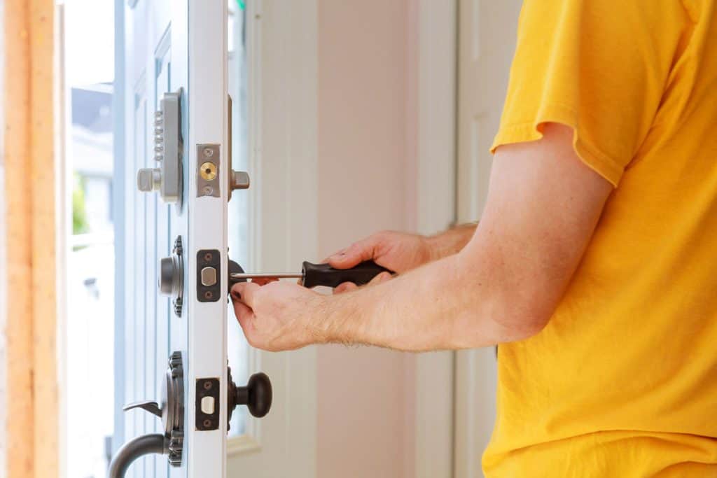 Worker installing a door lock to the front door