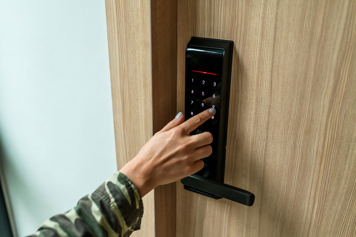 a woman's finger entering password code on the smart digital touch screen keypad entry door lock in front of the room