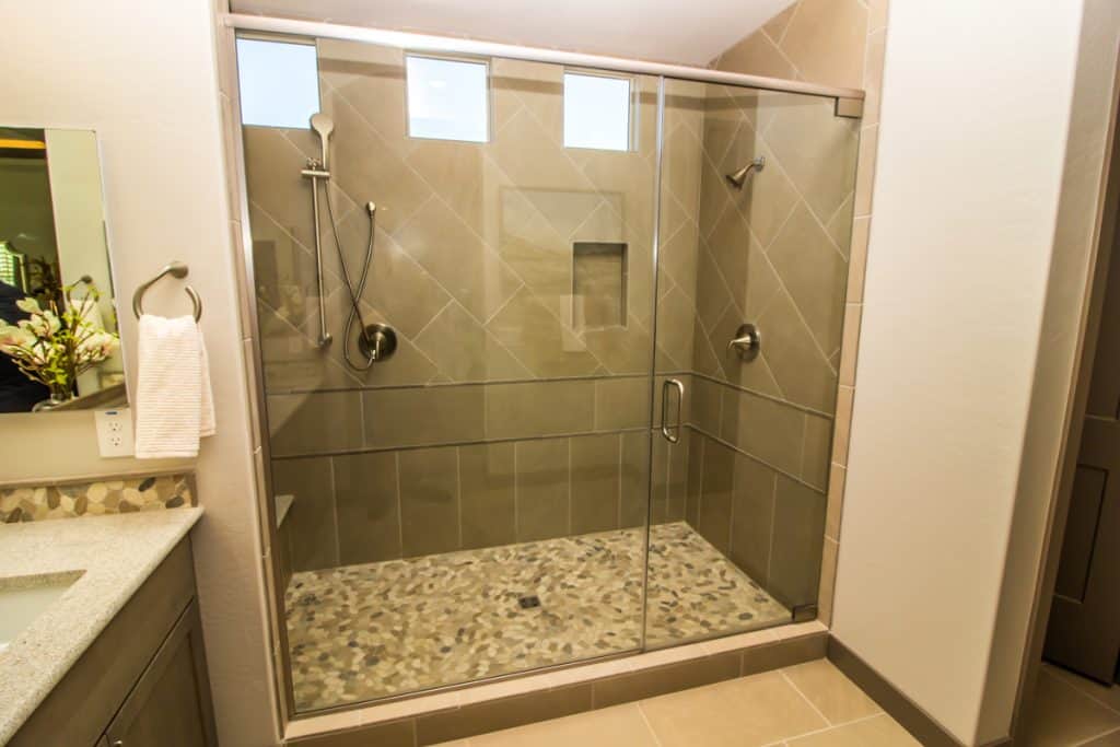 A luxurious modern bathroom with a glass shower area and marble tile walls