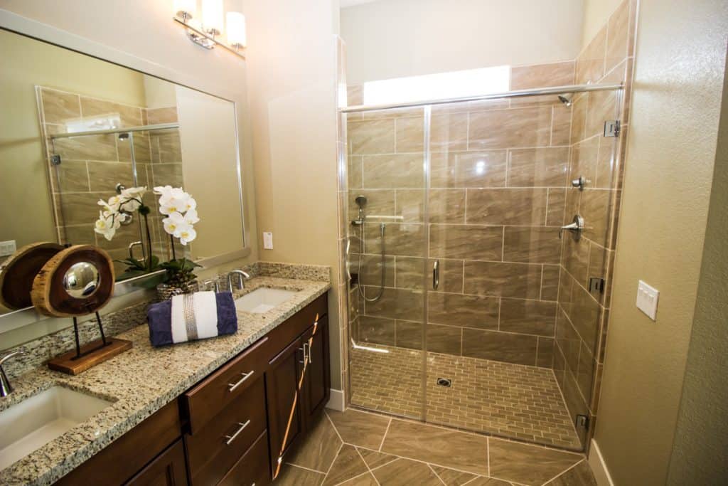 Luxurious bathroom interior with glass shower wall, marble countertop and a long span mirror on the vanity