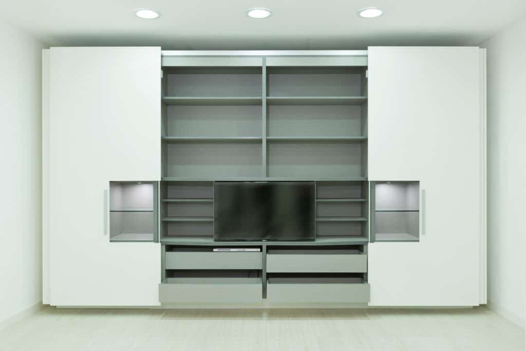 White and gray closet for TV room, with many shelves, drawers, compartments and sliding doors. Hiding cabinets. Modern design. Interior photography. Horizontal orientation.

