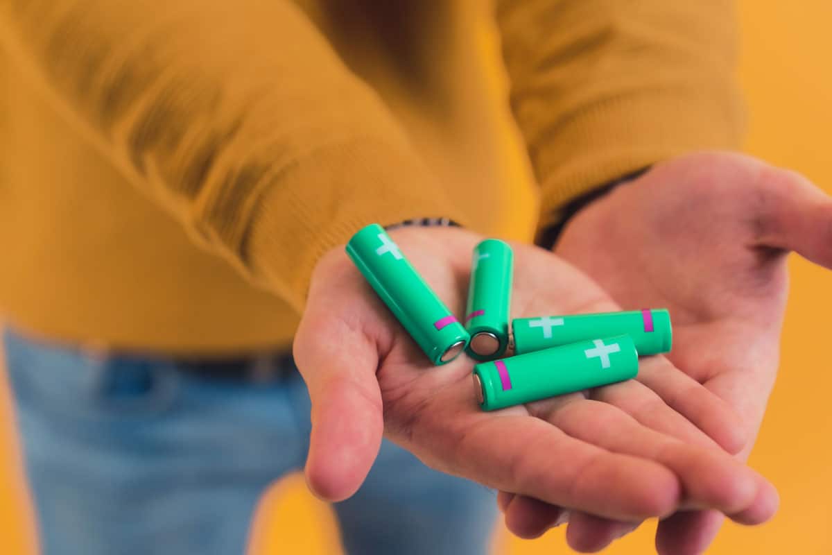 Batteries in male hands closeup studio shot yellow