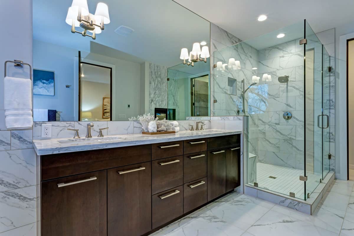 Incredible master bathroom with Carrara marble tile surround, modern glass walk in shower, espresso dual vanity cabinet an
