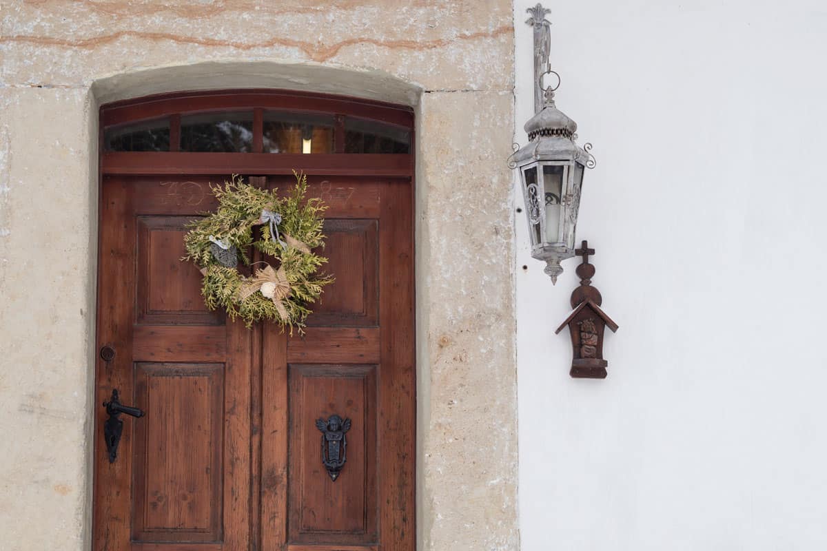 old wooden door with sandstone lining, wreath, lantern and cross