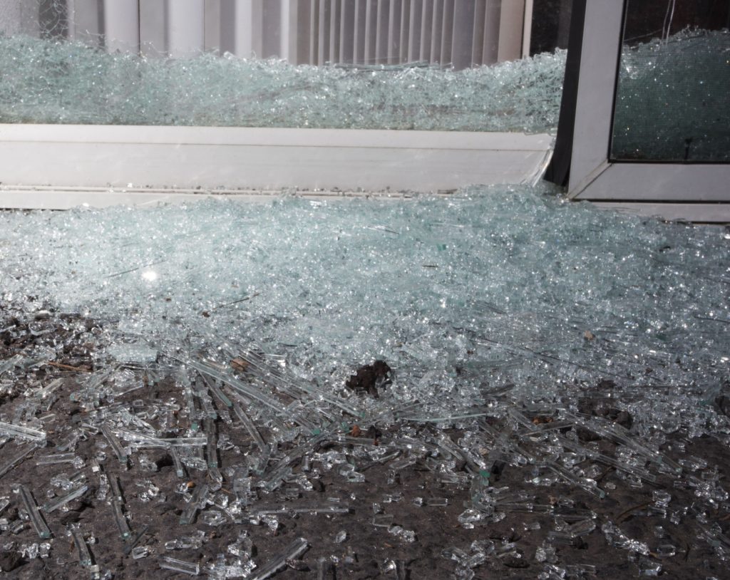 shattered glass on the floor next to a sliding door